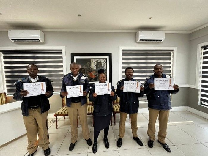 A group of people are standing in a room holding certificates.