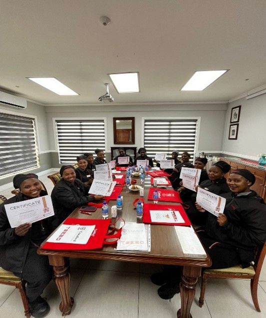 A group of people are sitting around a long table holding certificates.