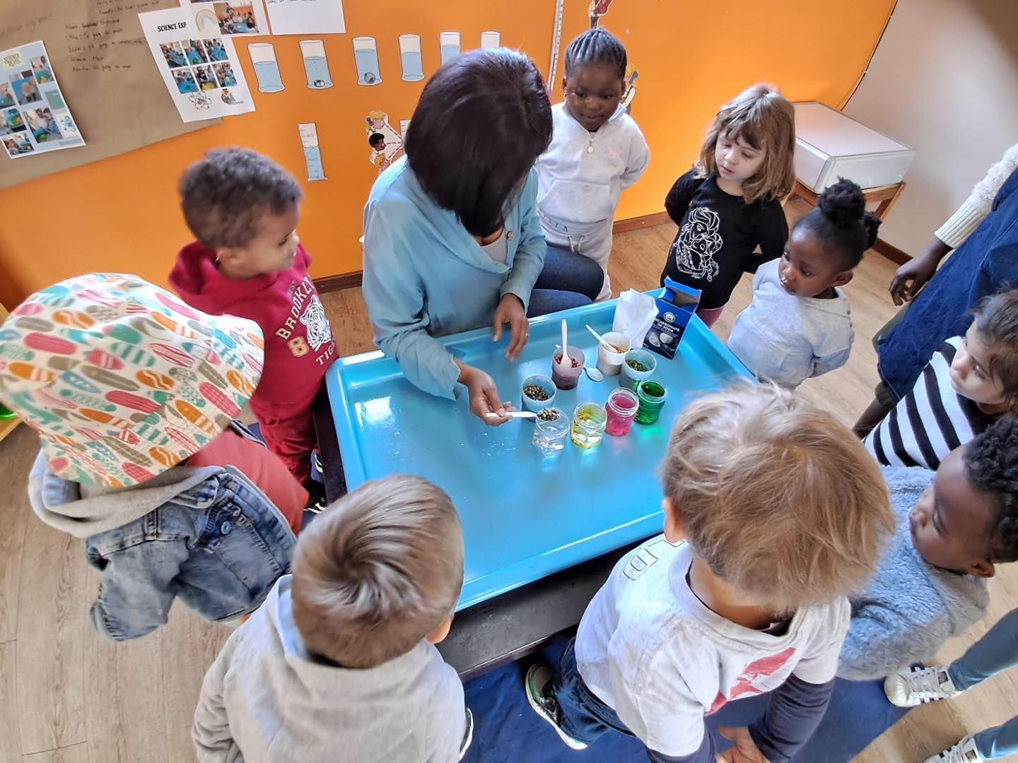 A group of children are sitting around a table with a woman.