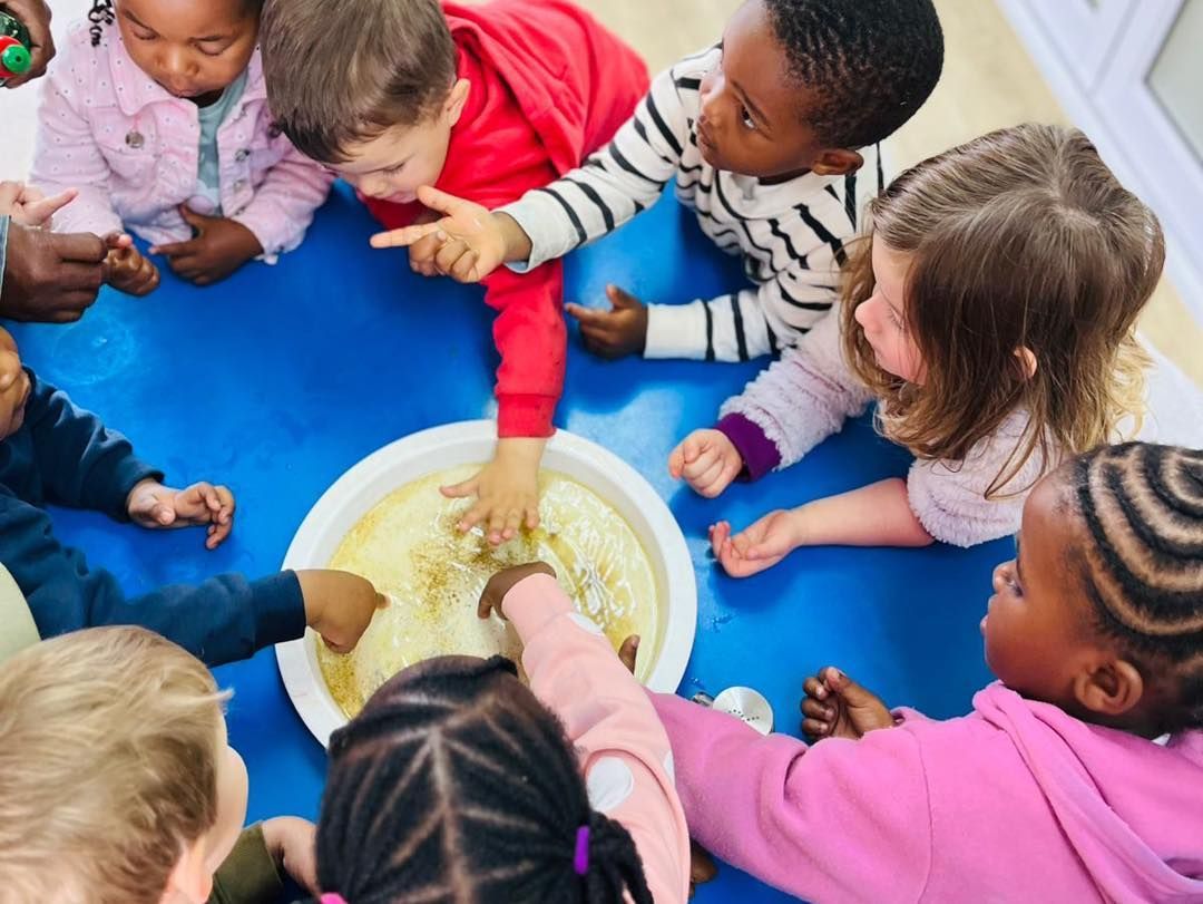 A group of children are sitting around a bowl of food.