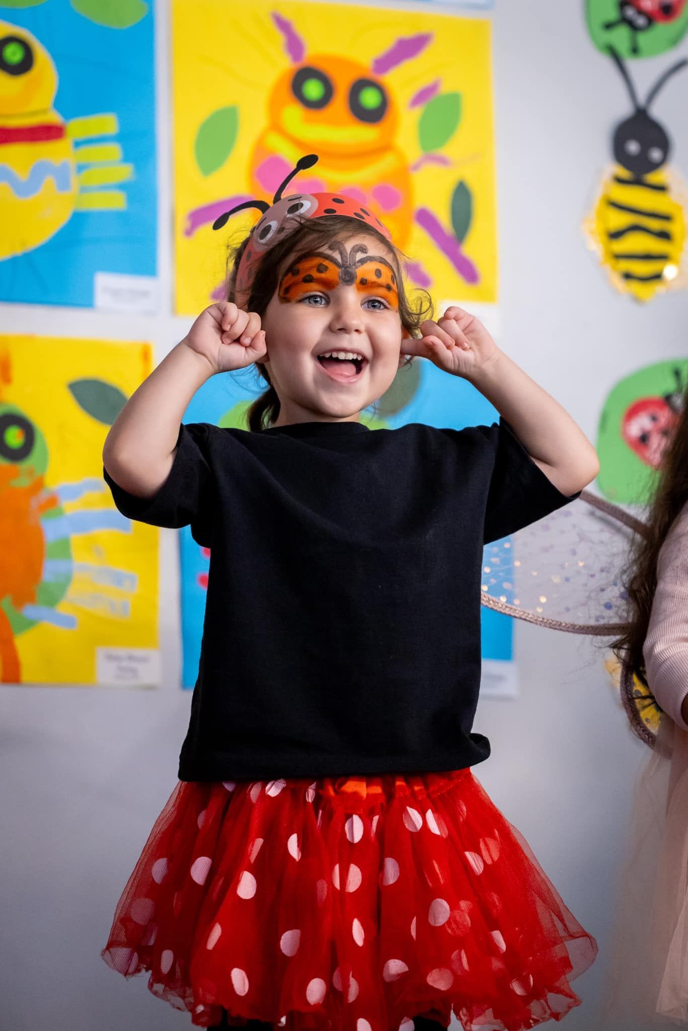 A little girl is wearing a black shirt and a red skirt.