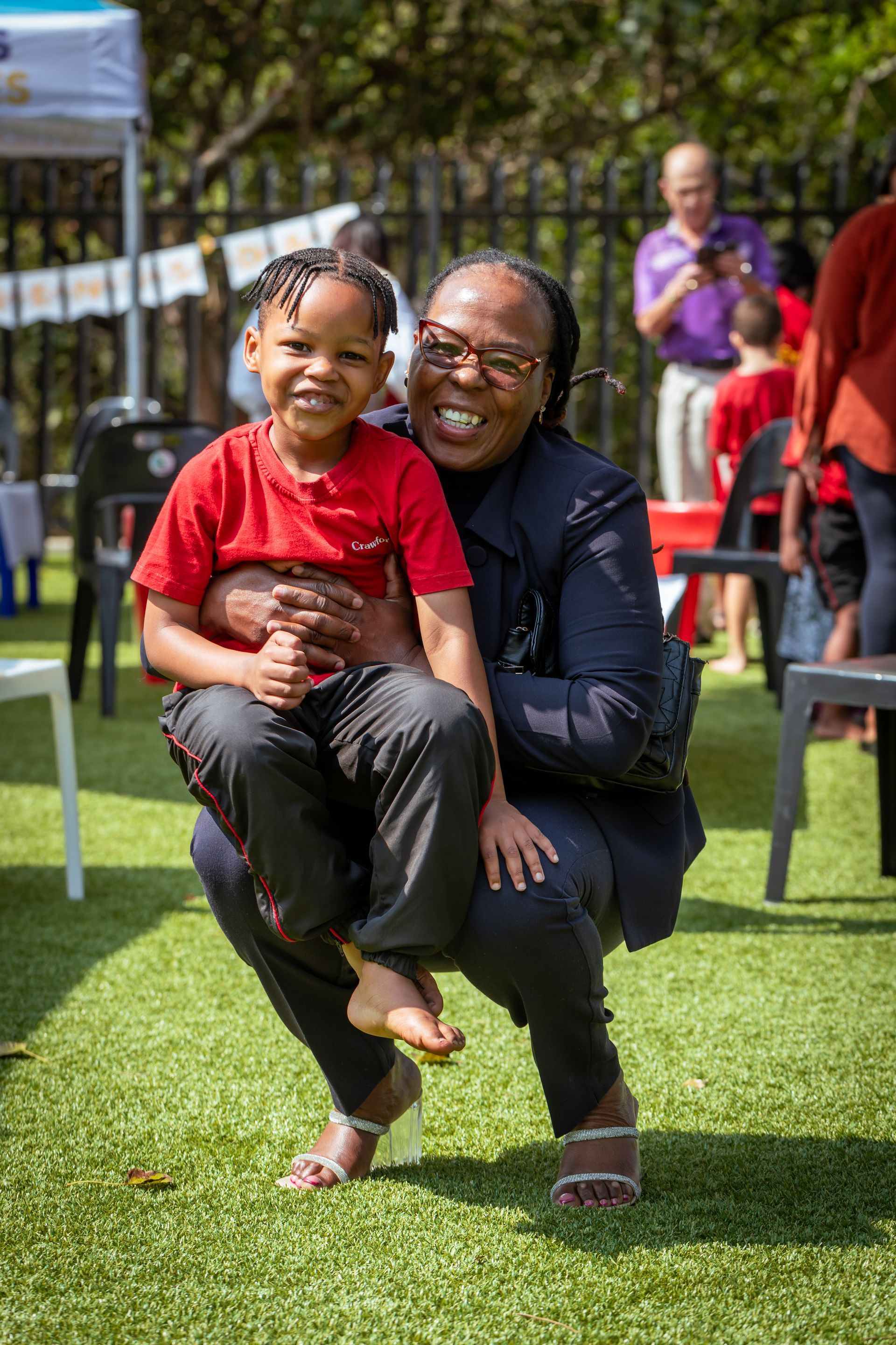 A woman is kneeling down holding a little boy in her arms.