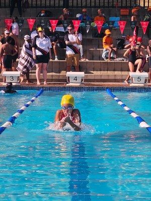 A girl is swimming in a pool with people watching.