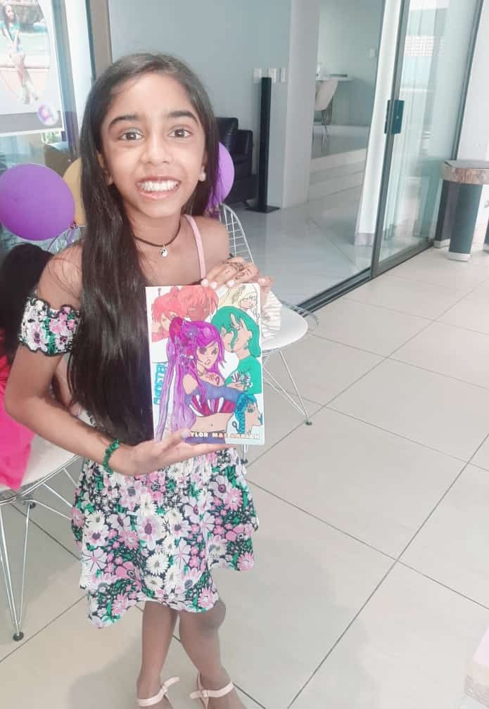 A little girl in a floral dress is holding a picture of herself.