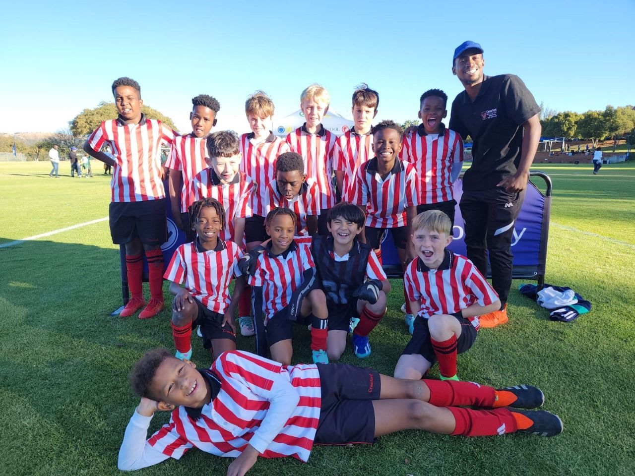 A group of young boys are posing for a picture on a soccer field.