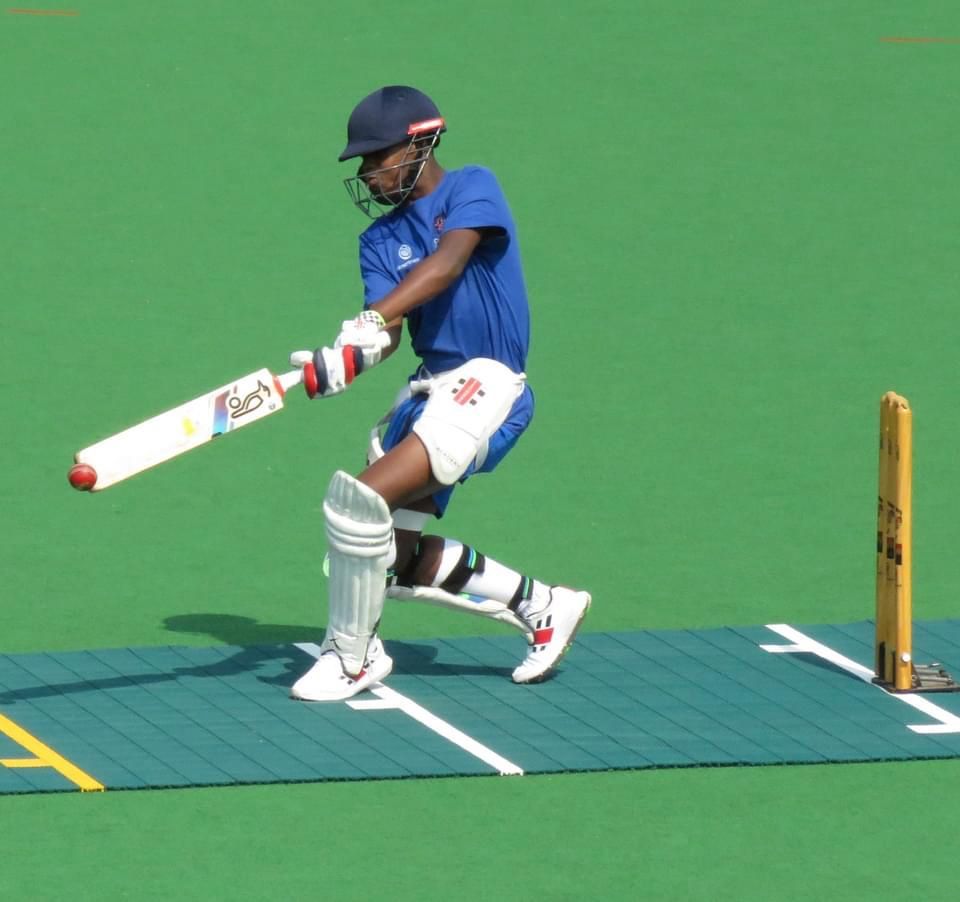 A man in a blue shirt is swinging a cricket bat