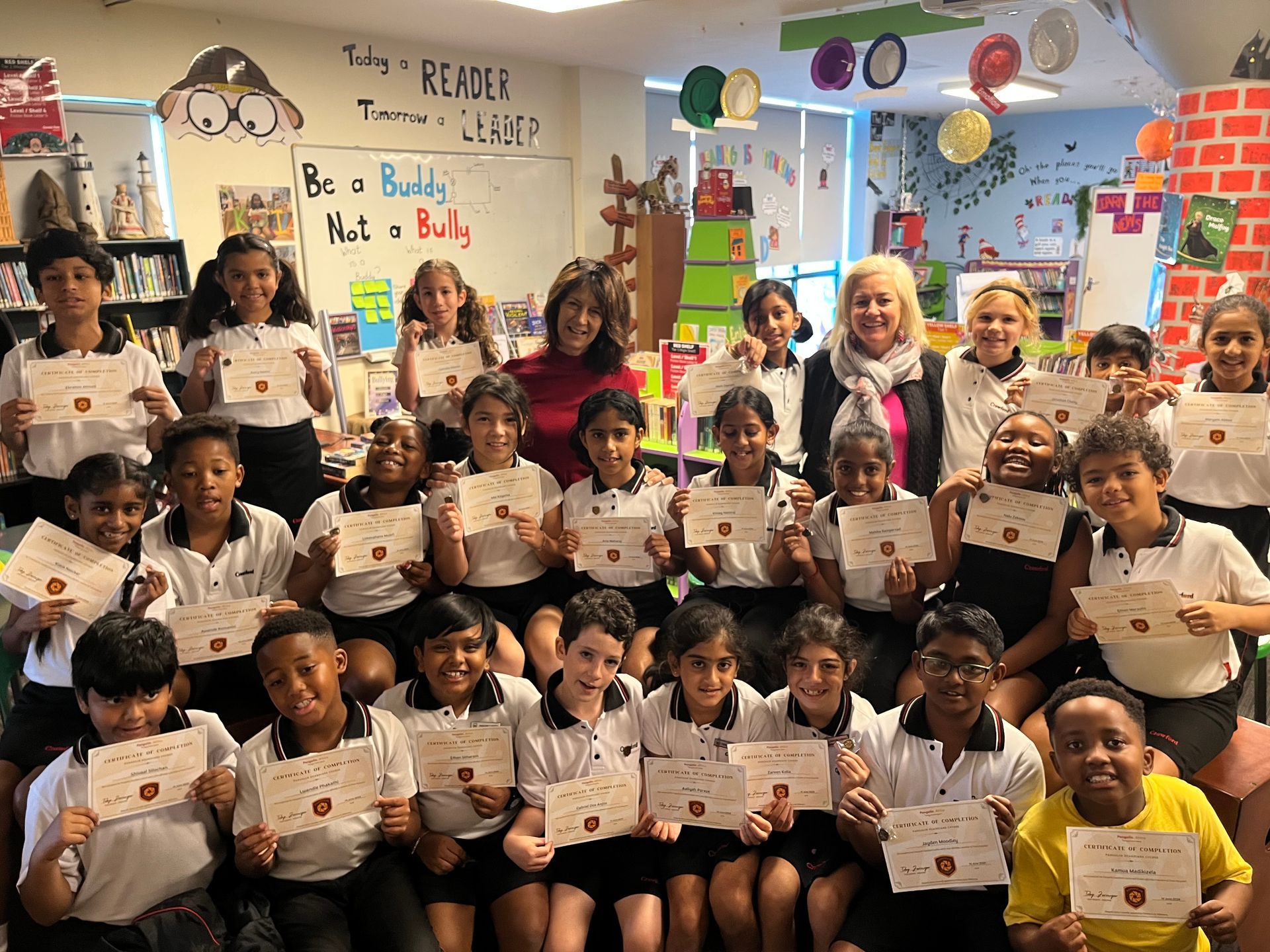 A group of children are posing for a picture in a classroom holding certificates.
