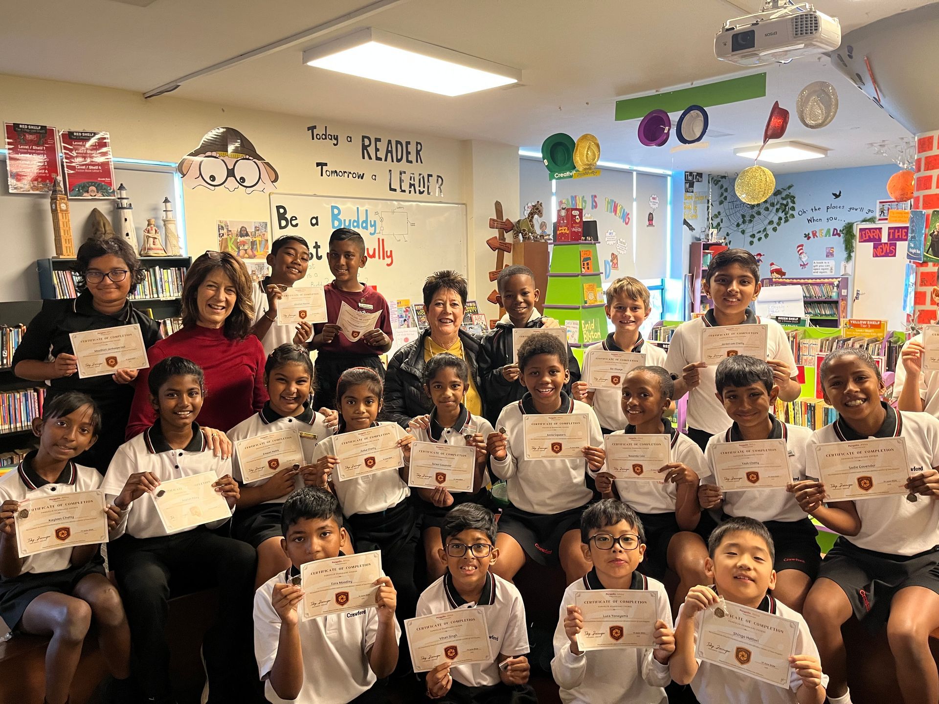 A group of children are posing for a picture in a classroom holding certificates.