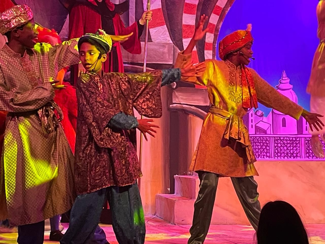 A group of people in costume are dancing on a stage.