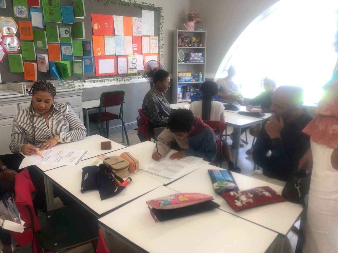 A group of people are sitting at tables in a classroom.