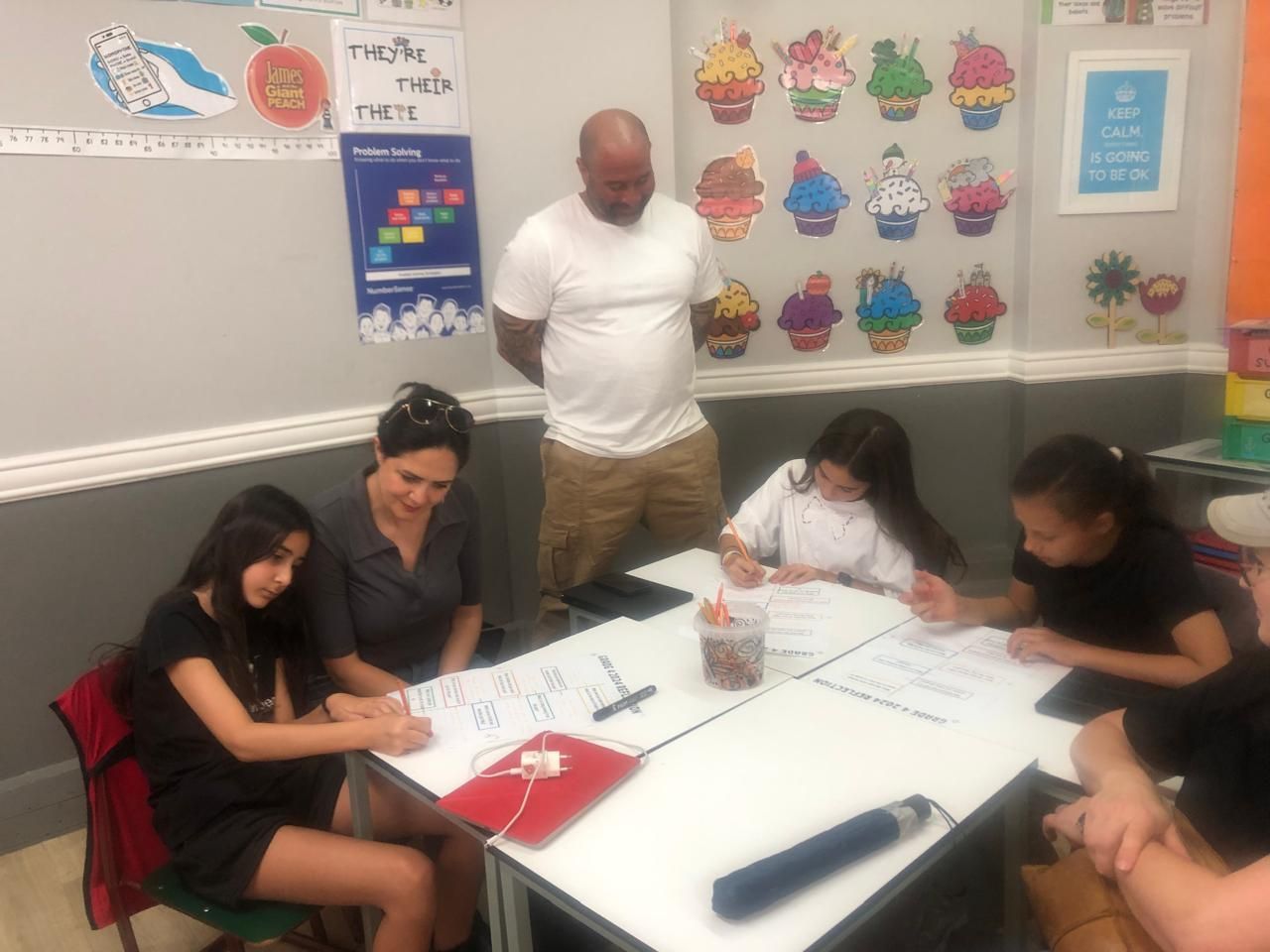 A group of people are sitting around a table in a classroom.