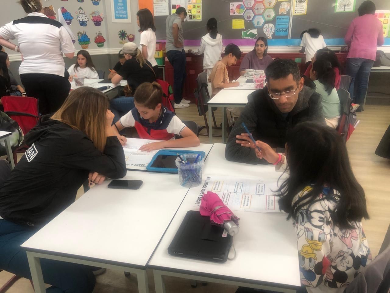 A group of people are sitting at tables in a classroom.