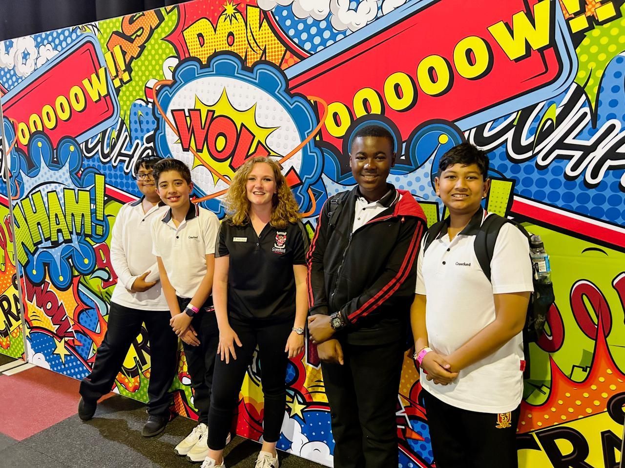 A group of young people standing in front of a comic book wall.