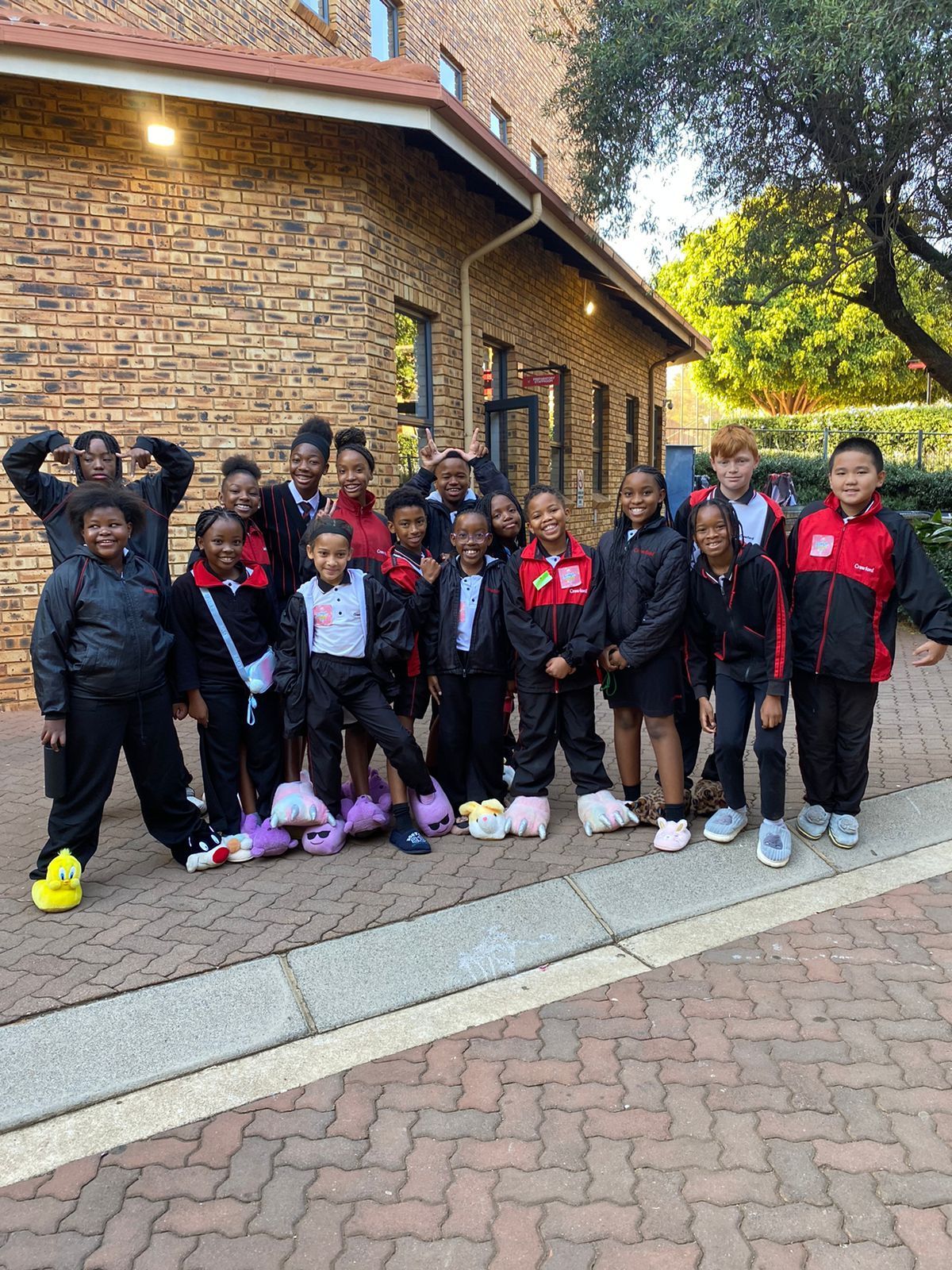 A group of children are posing for a picture in front of a brick building.