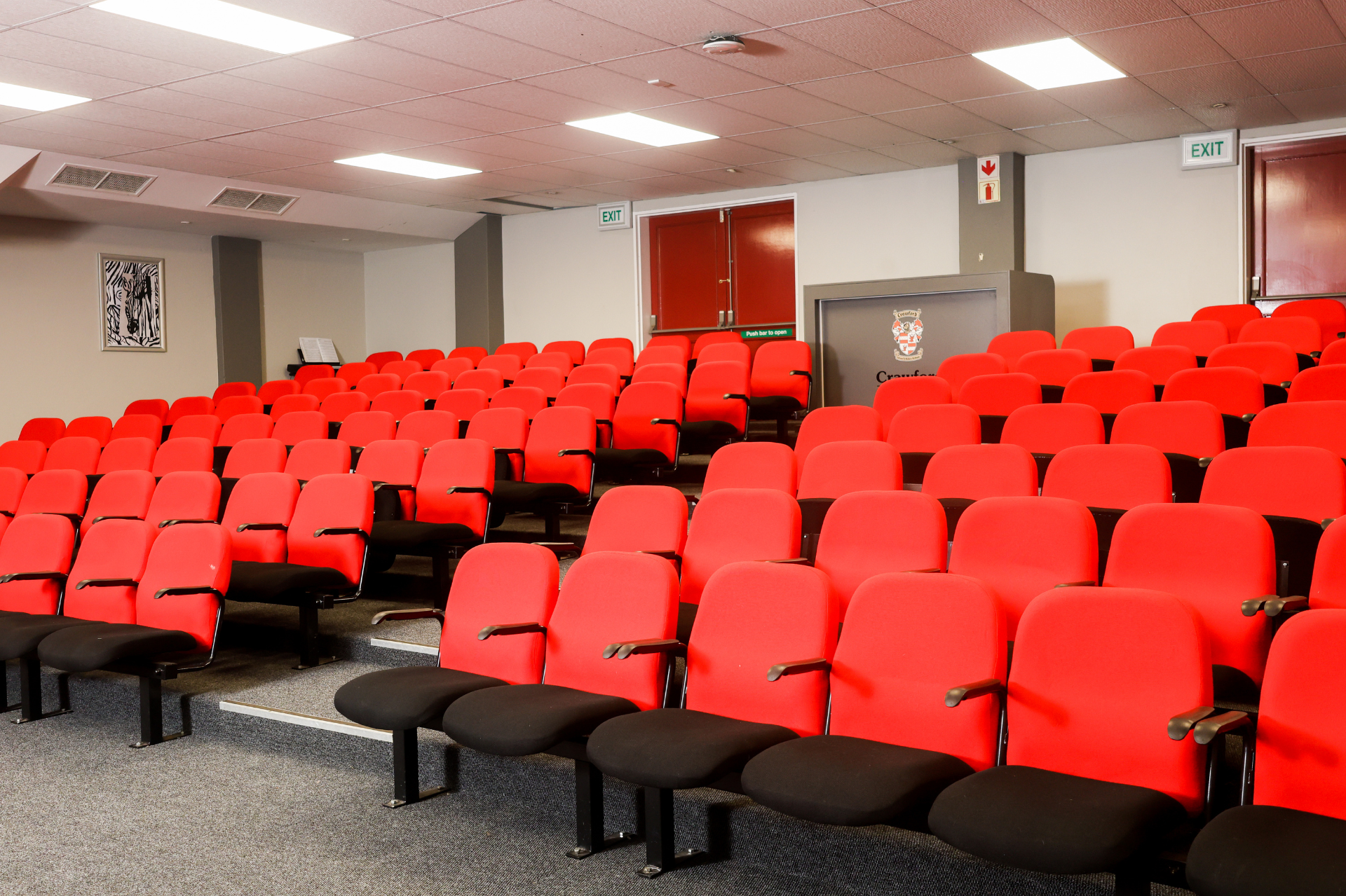 rows of empty chairs in an auditorium with a black curtain