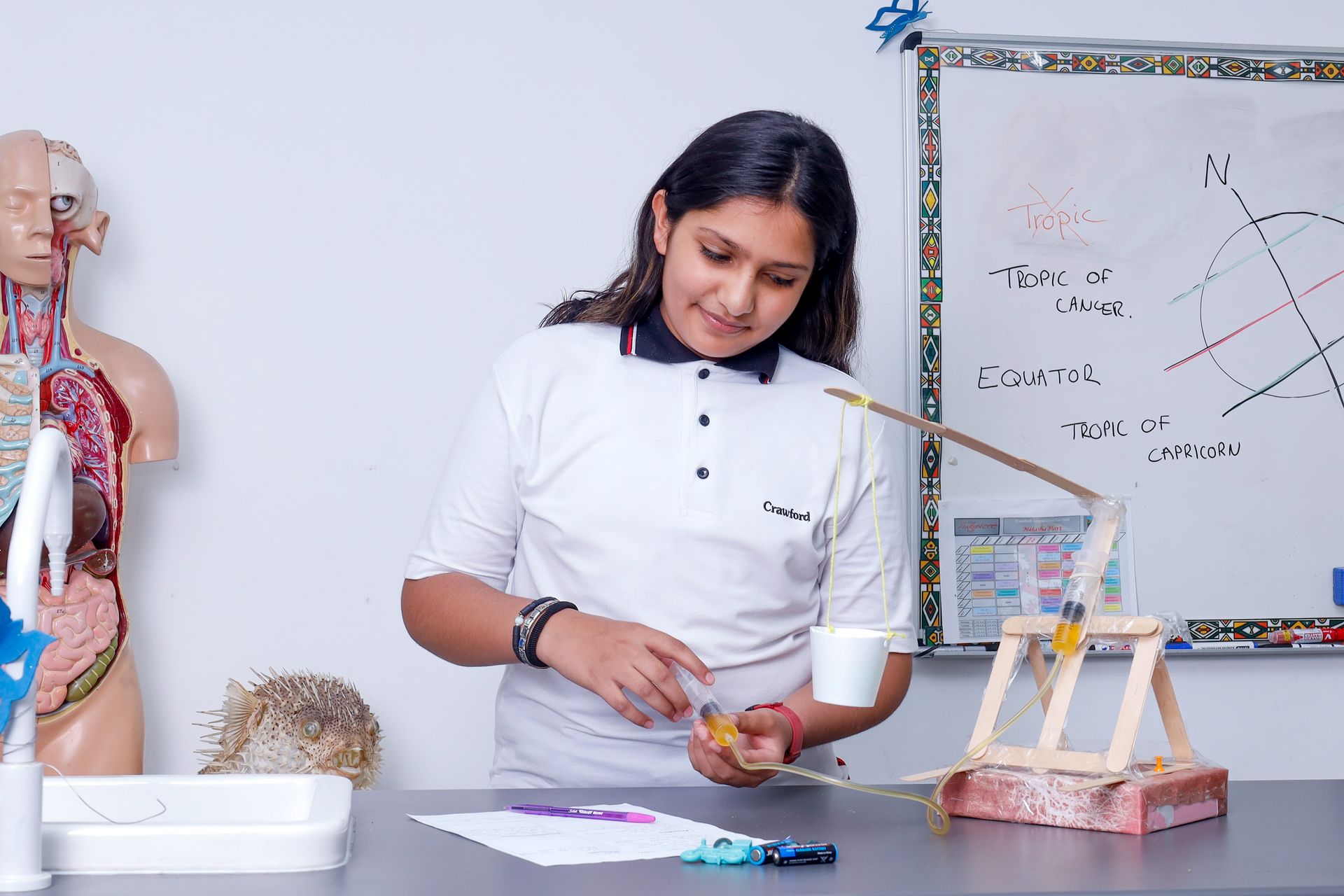 a young girl is standing in front of a whiteboard in a classroom .