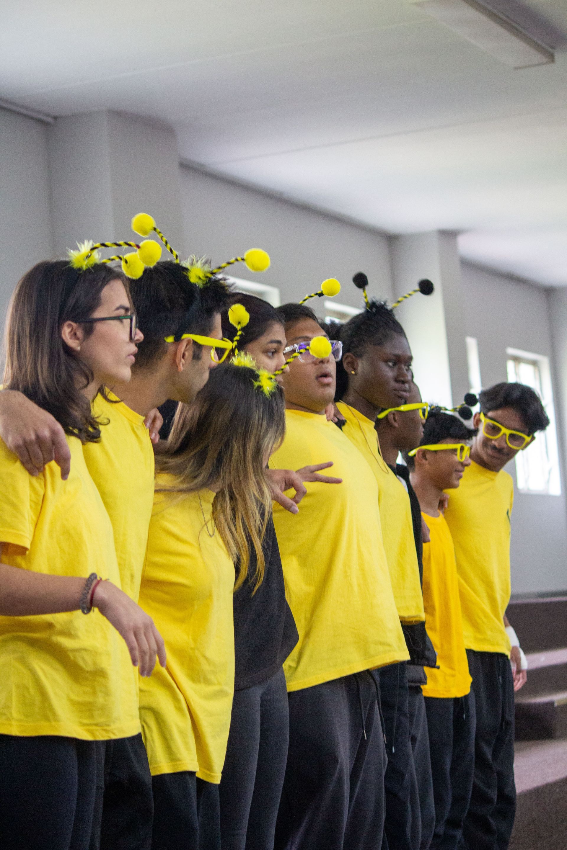 A group of people wearing yellow shirts and bee hats are standing next to each other.