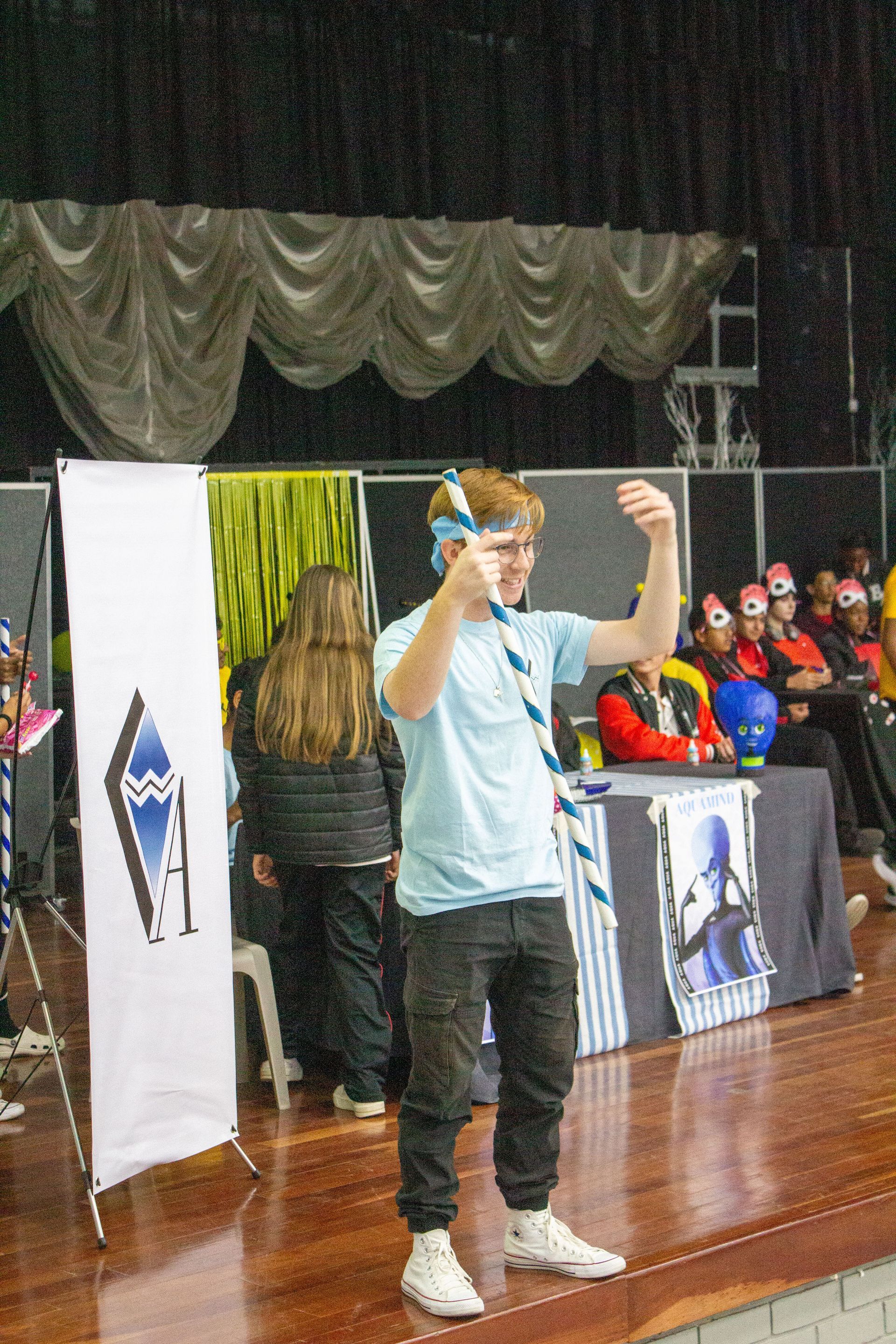 A young man is standing on a stage in front of a crowd.
