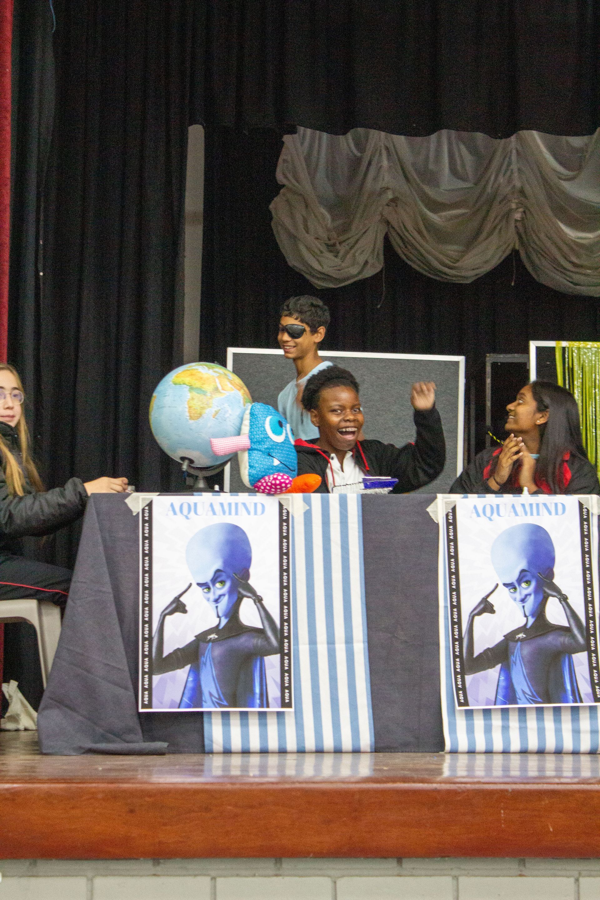 A group of people sitting at a table with posters on it that say aquamind
