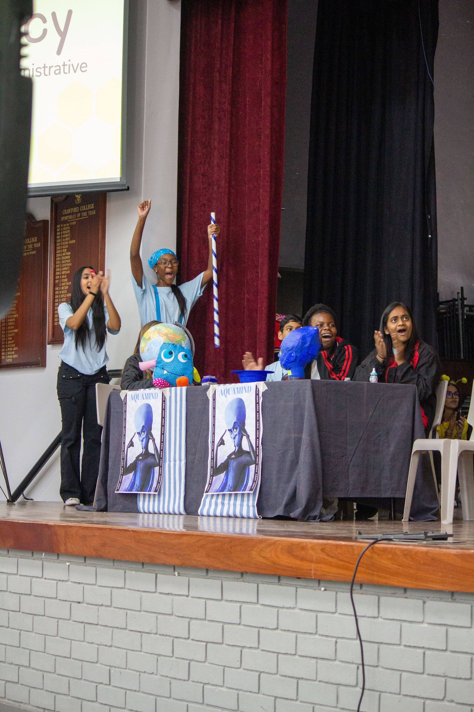 A group of people are sitting at tables in a room with a sign that says 