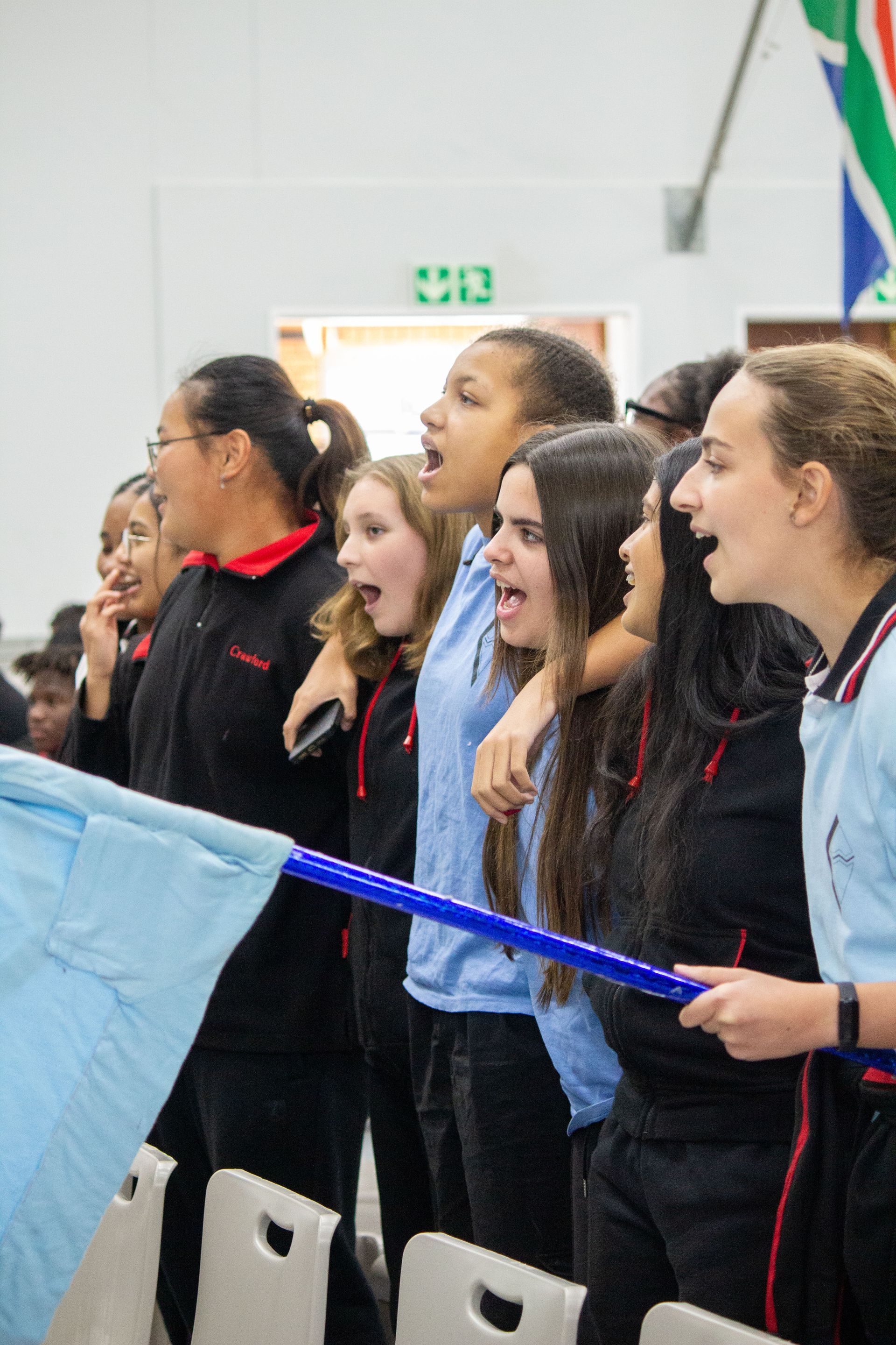 A group of young women are standing in a room holding a flag.