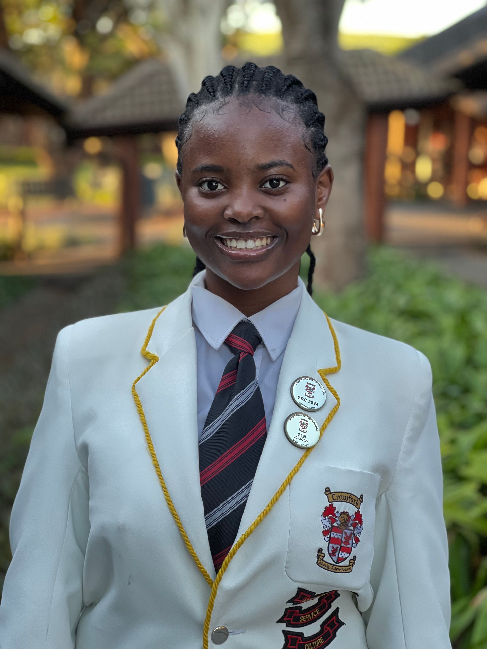 A woman wearing a white jacket and tie is smiling for the camera.