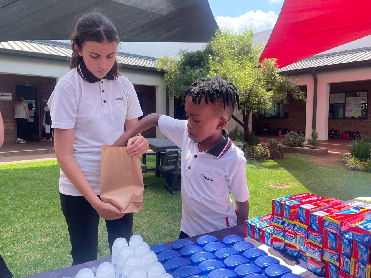 A girl and a boy are standing in front of a table filled with ice cubes.