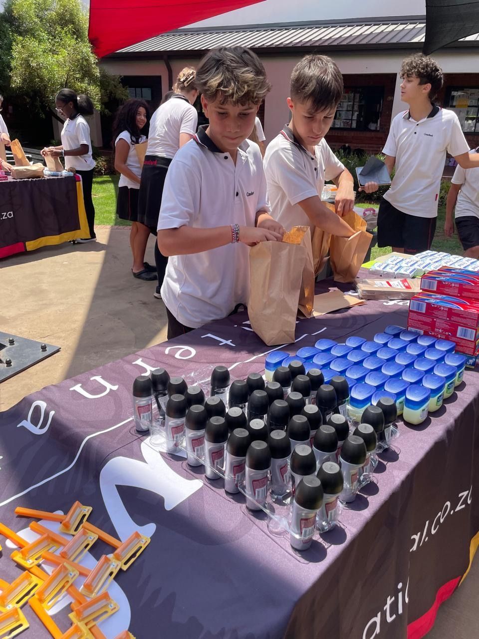 A group of children are standing around a table with bottles on it