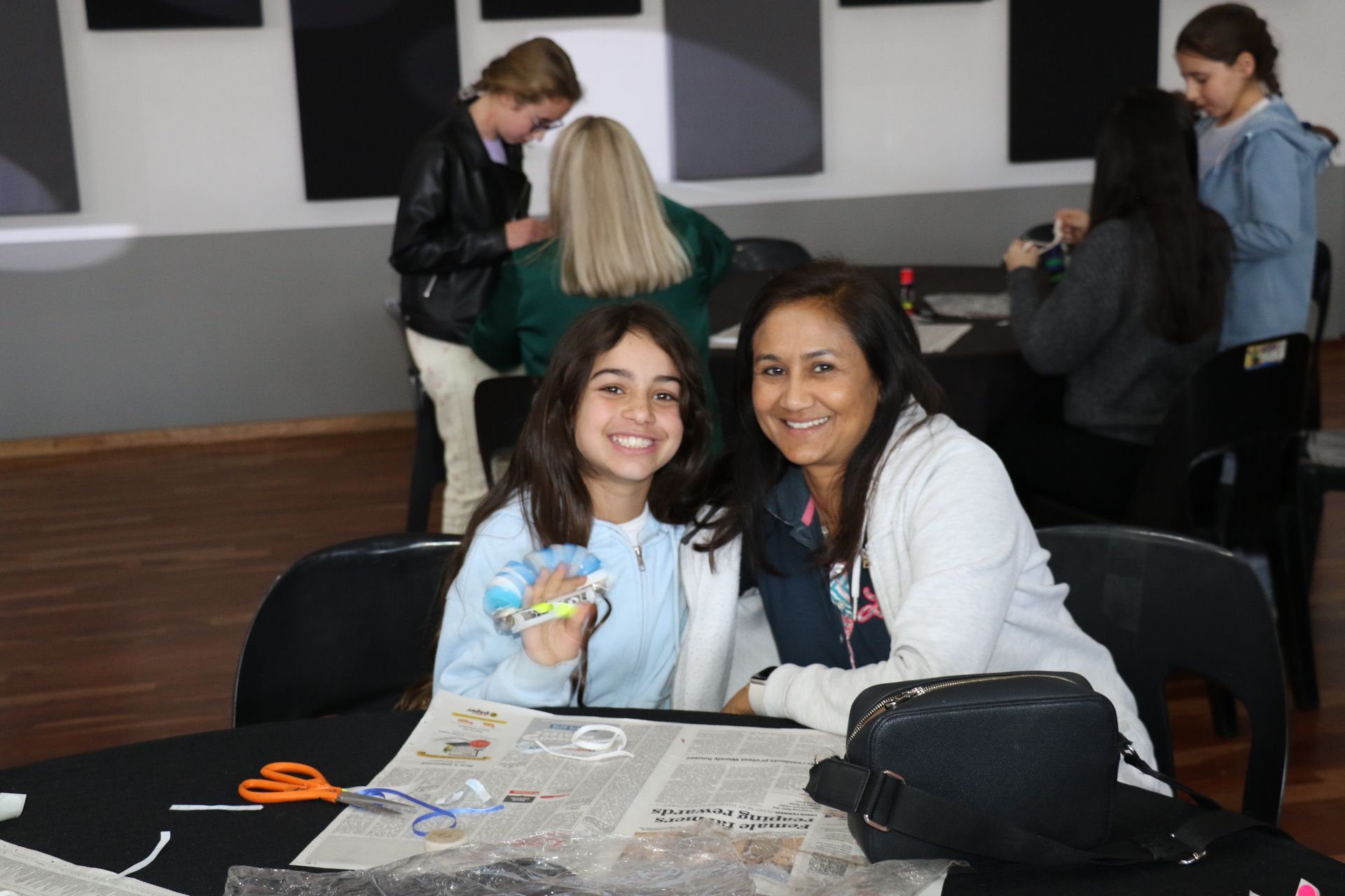 A woman and a girl are sitting at a table with scissors.