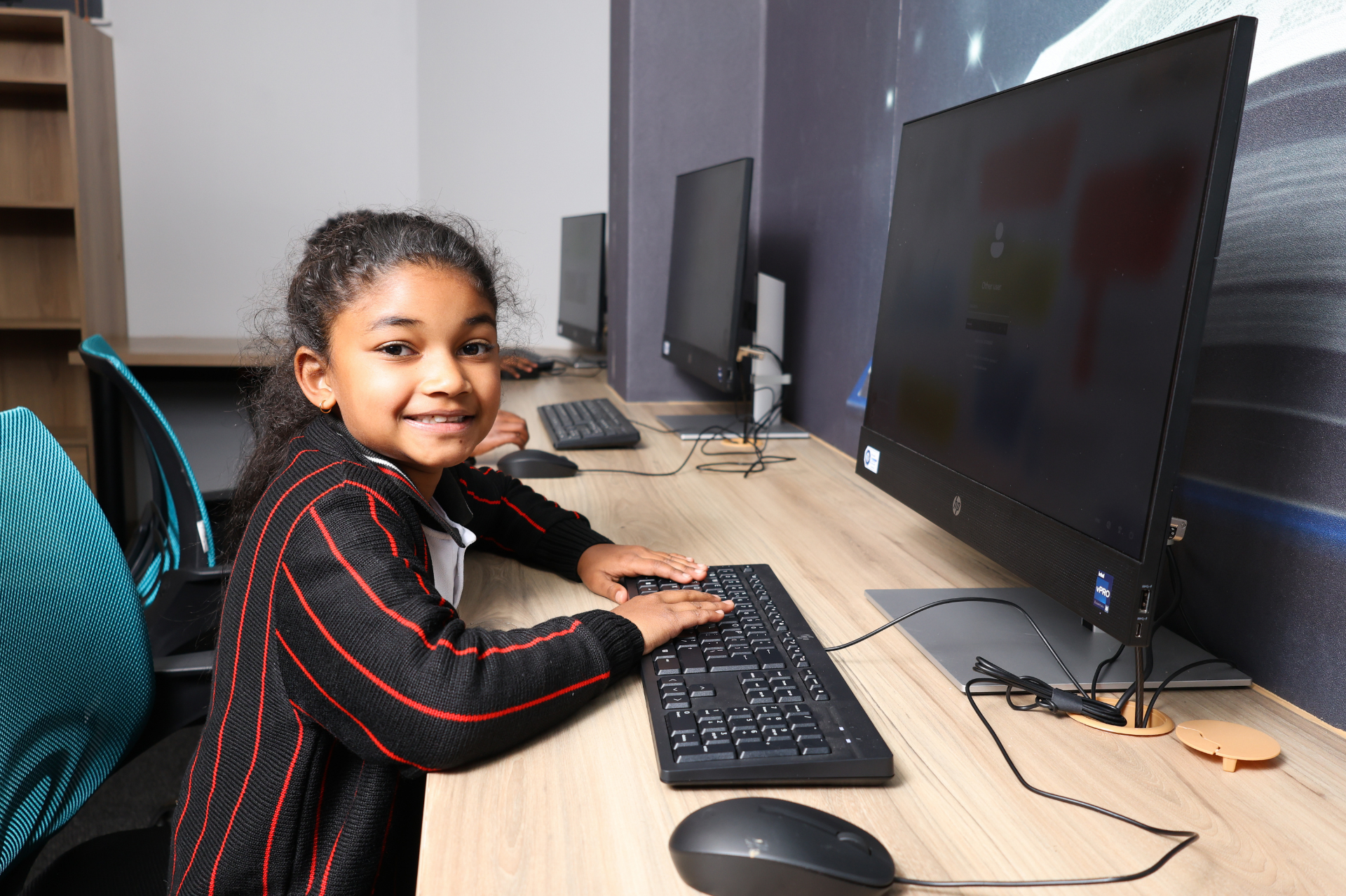 a boy and two girls are sitting at a table in a classroom .