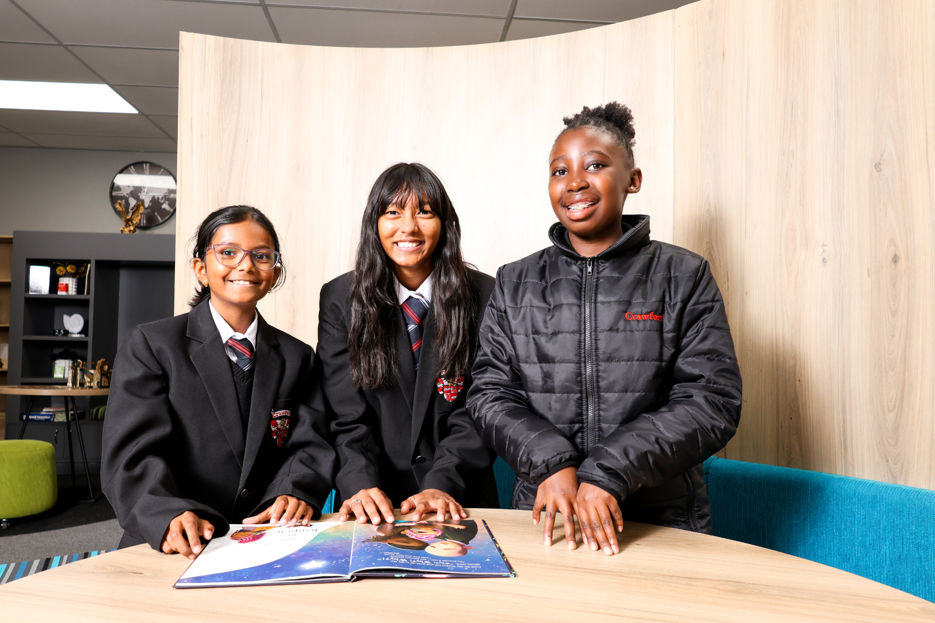 a young boy is sitting at a desk in a classroom writing on a piece of paper .