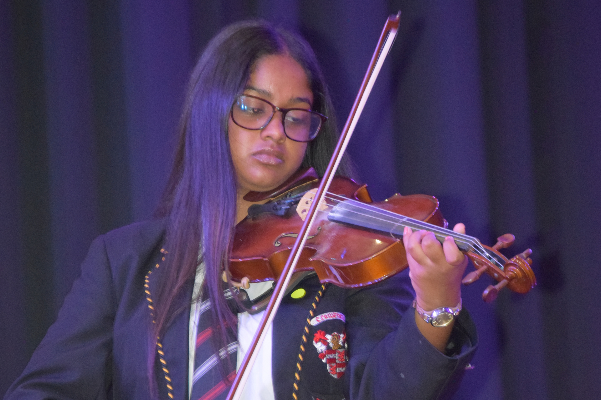 a young girl is playing a violin in front of a poster of pianos