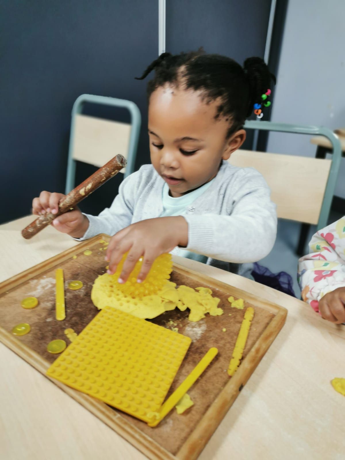 A little girl is playing with yellow blocks on a table
