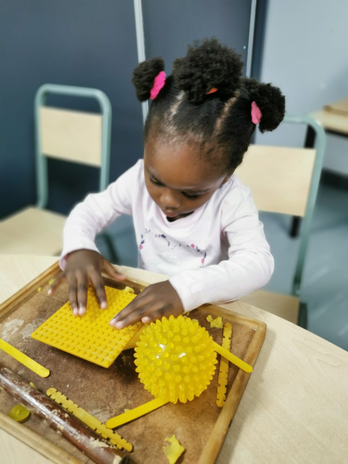 A little girl is playing with yellow toys on a table