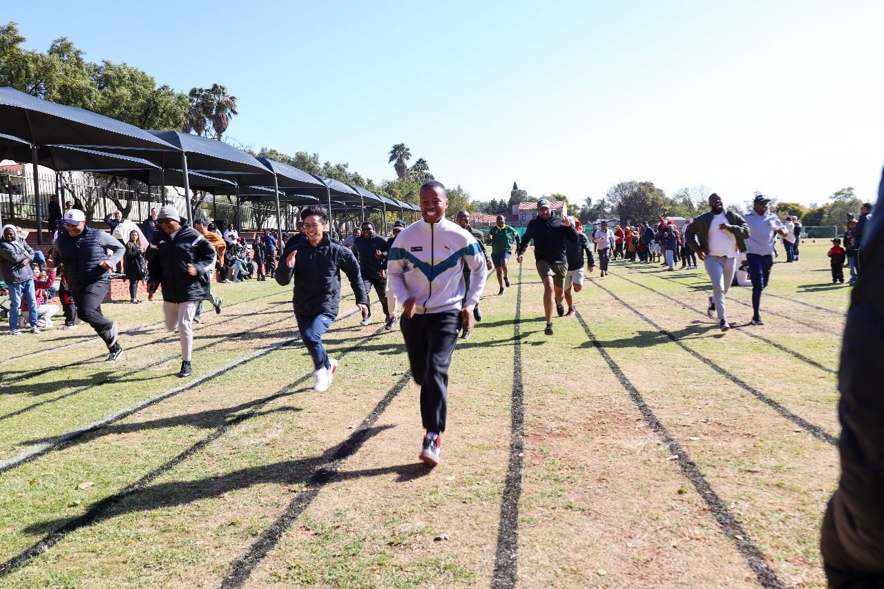 A group of people are running on a track in a field.