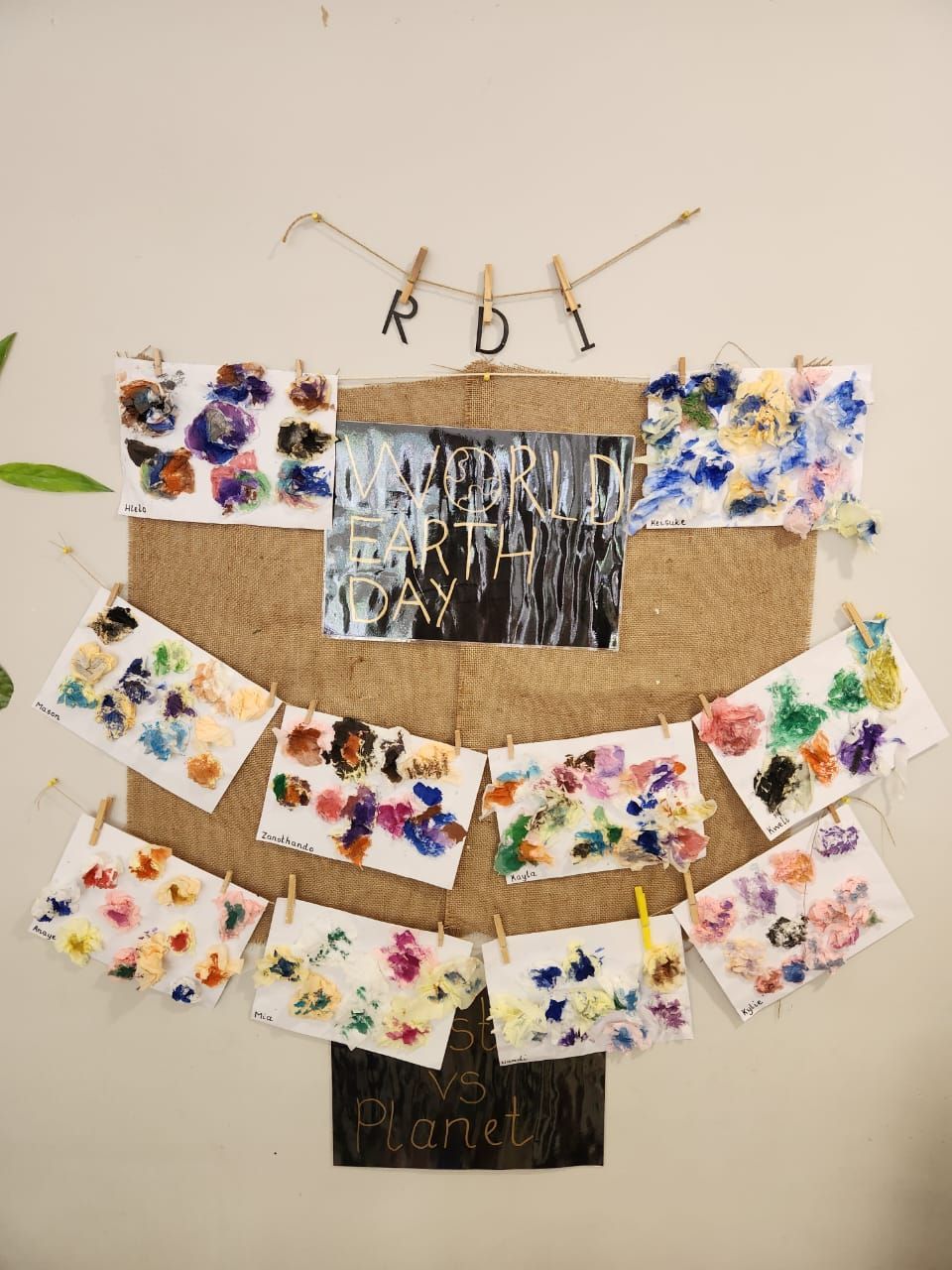 Artwork display: painted cards pinned to burlap, a central photo, and 