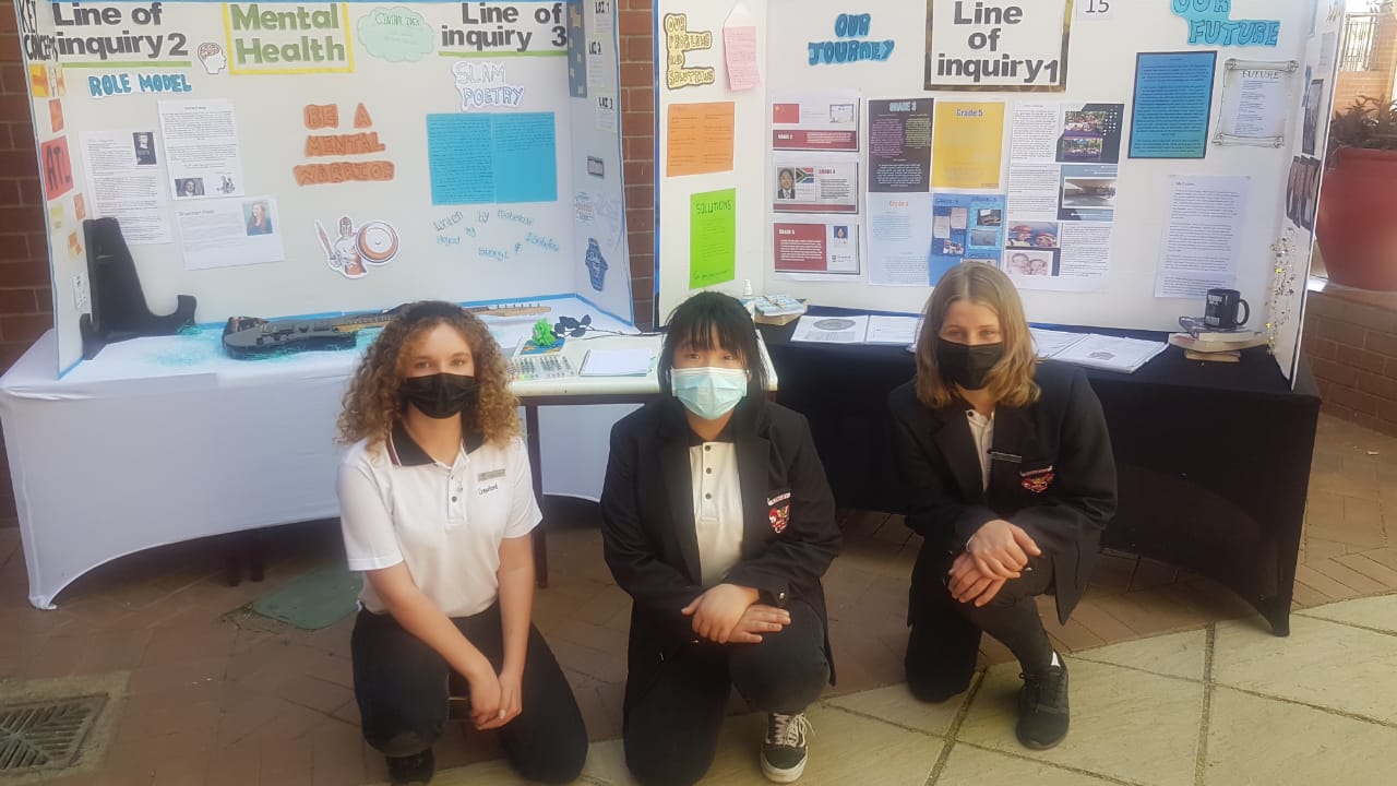 Three girls wearing masks are kneeling in front of a table.