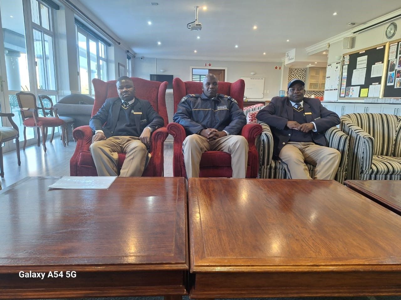 Three men are sitting in chairs in a living room.