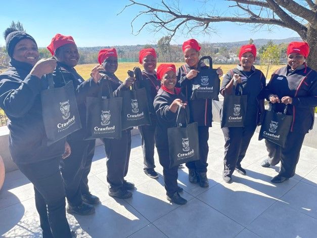 A group of people standing next to each other holding bags.