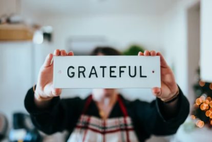 Person holding up a white card with the word grateful written on it