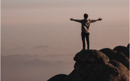 Young man with outstretched arms on a cliff