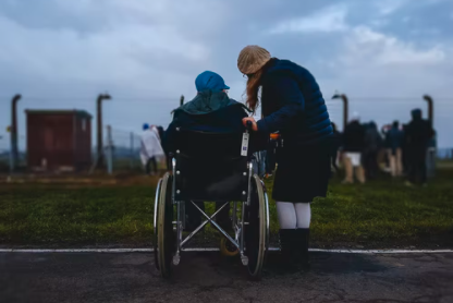 Young girl standing next to someone in a wheelchair, making a difference