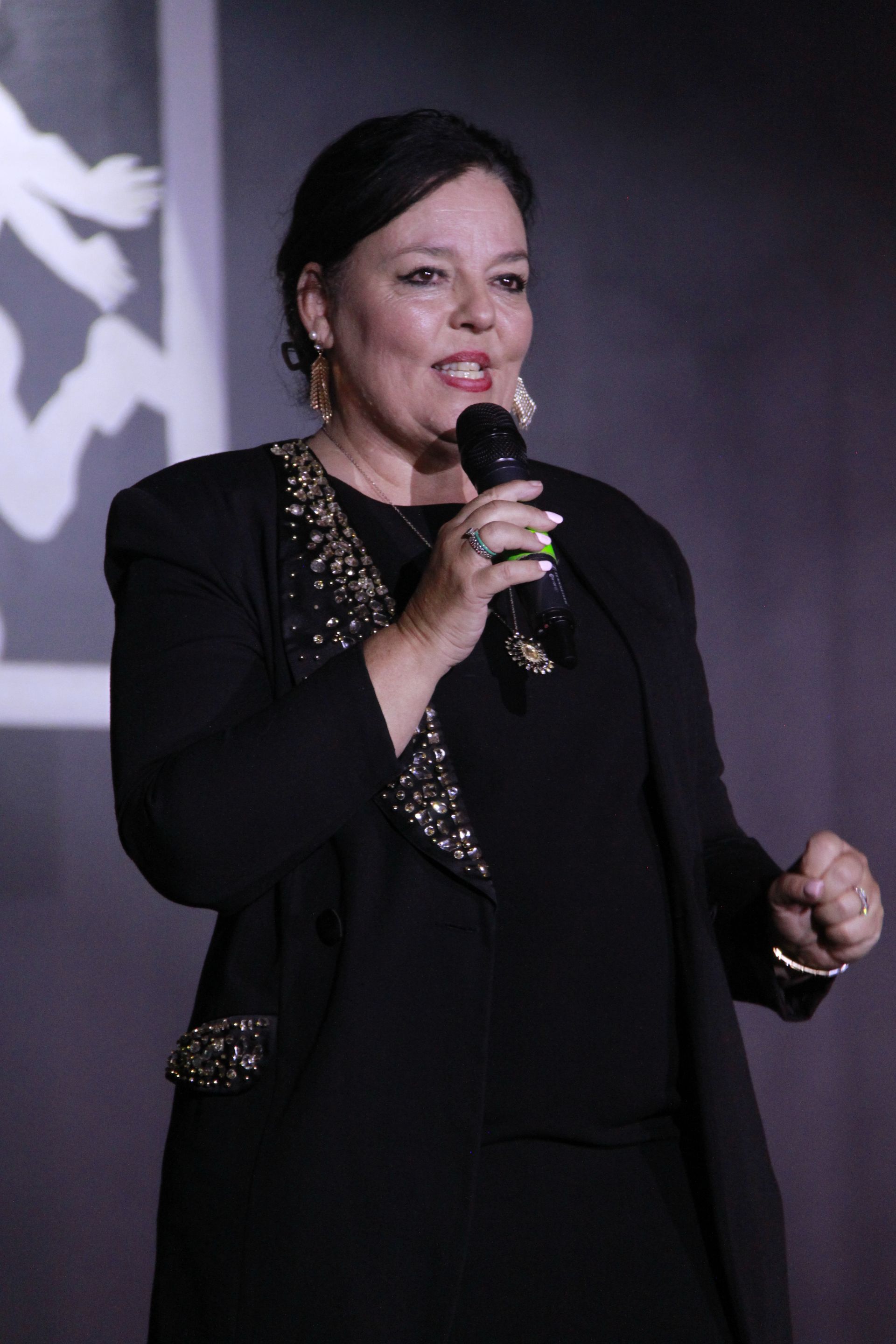 A woman in a black dress is singing into a microphone.