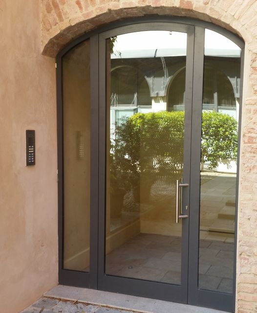Si.za- rottofreno-una porta in vetro e ferro di color nero in uno stabile con mattoni in pietra color sabbia