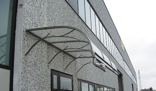 Si.za- rottofreno-vista laterale di una tettoia in vetro a forma curva in uno stabile con facciata grigia