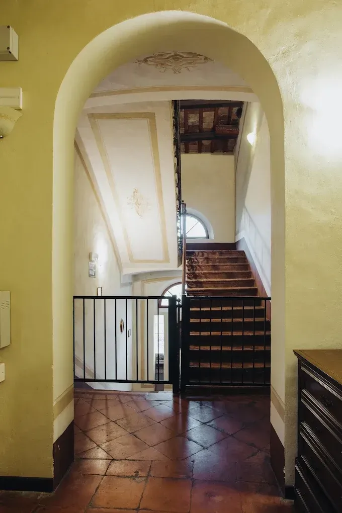 Porta ad arco che conduce a una scala in un edificio con pavimenti in cotto e soffitti decorati.