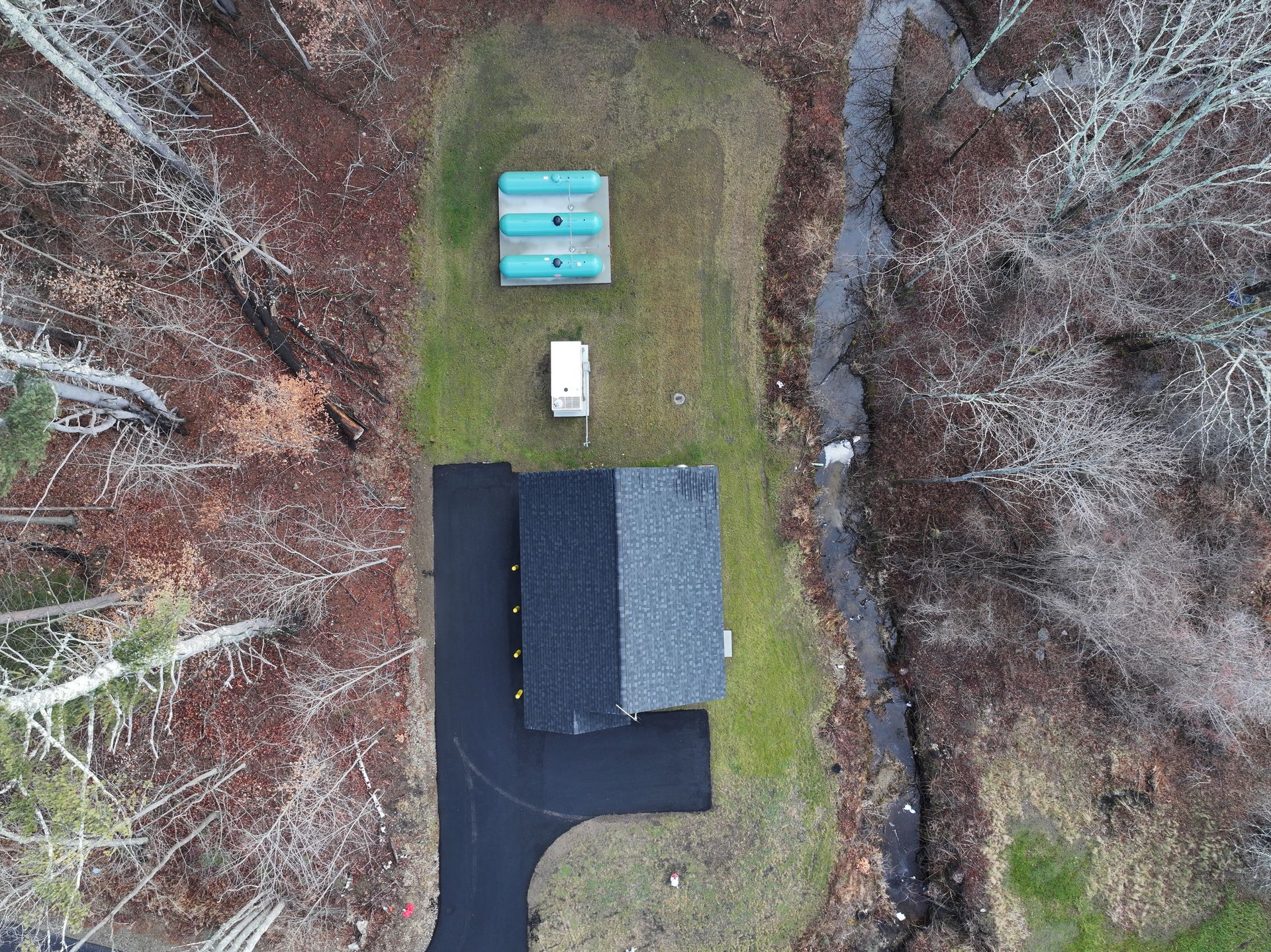 An aerial view of a house in the middle of a forest.