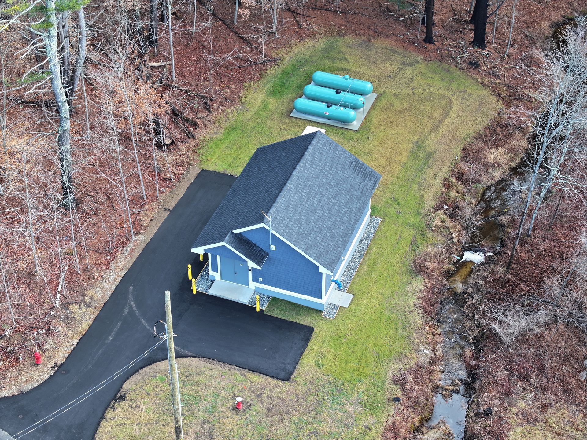 An aerial view of a blue house in the middle of a forest