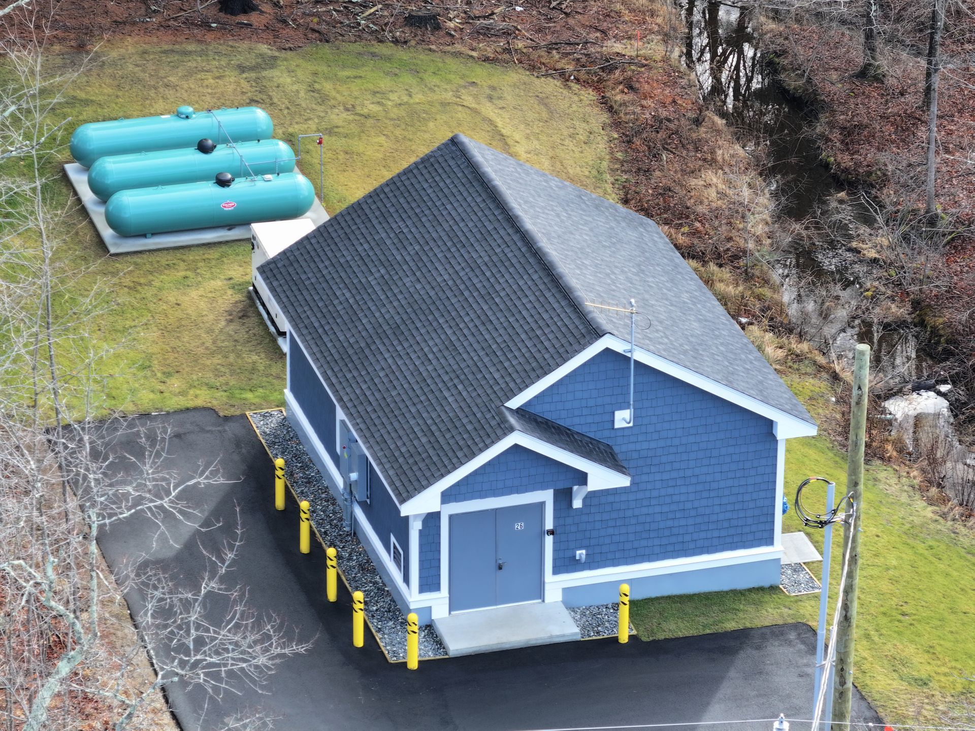 An aerial view of a blue water utility building with three propane tanks behind it