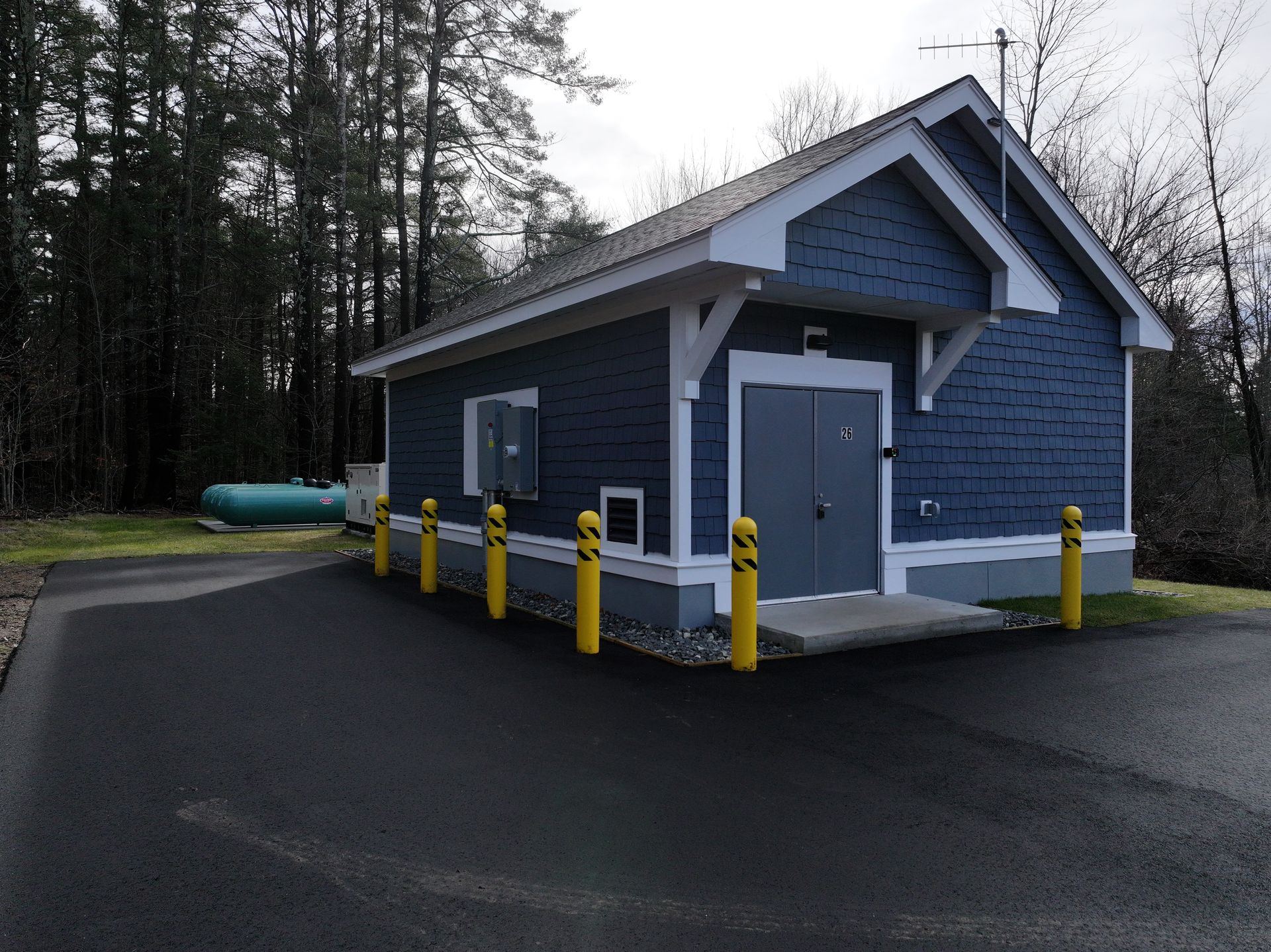 A small blue building with yellow poles in front of it